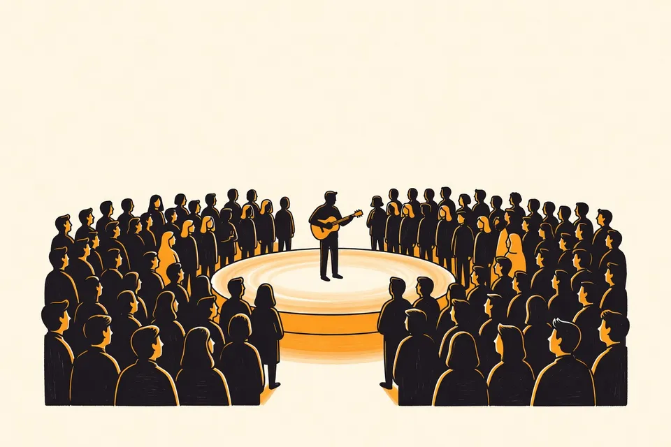 A wide view of a dimly lit hall with a circular stage in the center. A musician stands on stage with a guitar, surrounded by a closely packed audience on all sides, creating an intimate atmosphere.